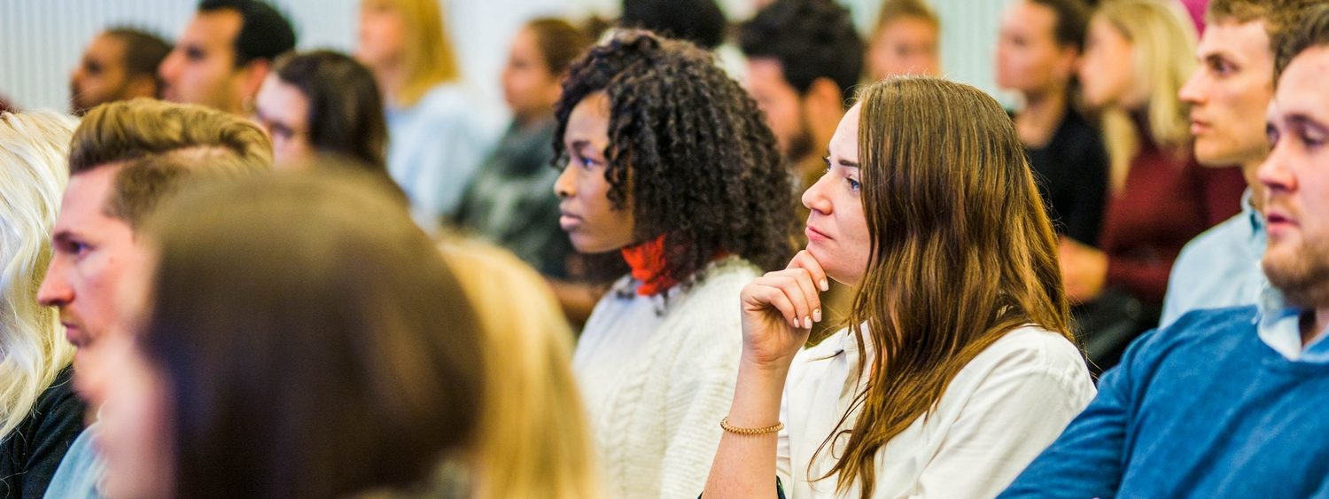 female student in an audience looking at speaker on stage